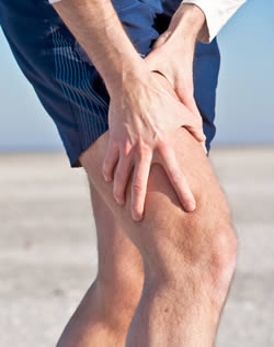 Photo of man in shorts holding knee, presumably because it hurts.