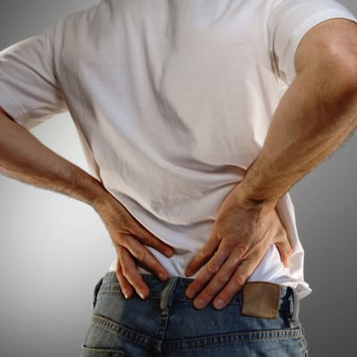 Photo of a man holding his stiff back.