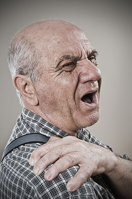 Photograph of an aging gentleman grasping his shoulder with a pained expression, representing the potential severity of trigger point pain.