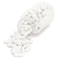 Photograph of a clear bottle of plain white pills spilling out onto a white surface.