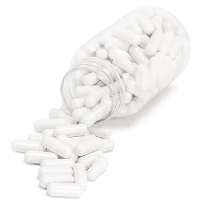 Photograph of a clear bottle of plain white pills spilling out onto a white surface.