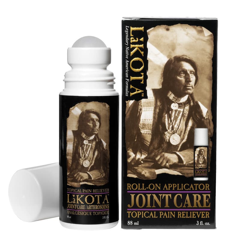 The image shows a product called “Lakota Joint Care,” a topical pain reliever with a roll-on applicator. The bottle and box feature a sepia-toned image of a Native American man dressed in traditional attire, including a beaded necklace and a medallion. The packaging emphasizes the use of “Legendary Native American Formulas” and highlights that the product is designed for joint care and arthritis relief. The bottle cap is removed, revealing the roll-on applicator. The product comes in an 88 ml (3 fl. oz.) container.