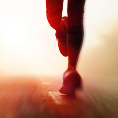 Bright, blurry, warm-toned photo of legs running on pavement.