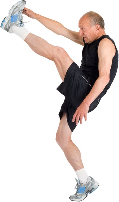Photo of an elderly man standing on one leg, kicking the other up high to his hand. He looks like he’s trying really hard.