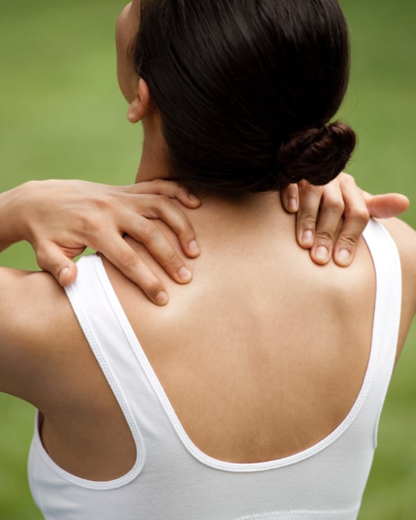 Photo of a woman holding her sore shoulders.