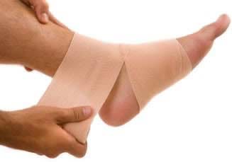 Photograph of an ankle being taped with a compression bandage for a sprain.