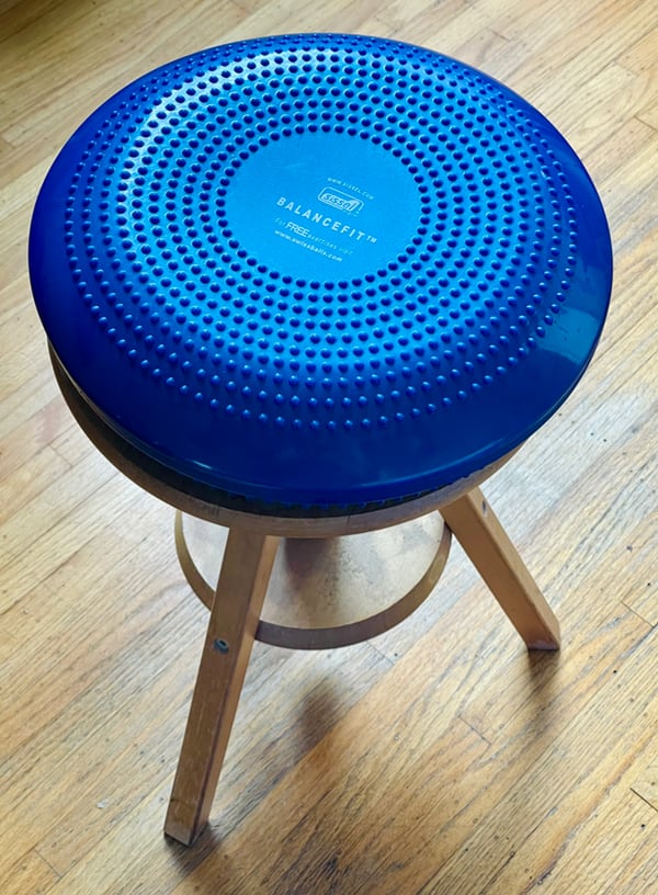 Photo of a bright blue Balance Fit sitting on a wooden stool.