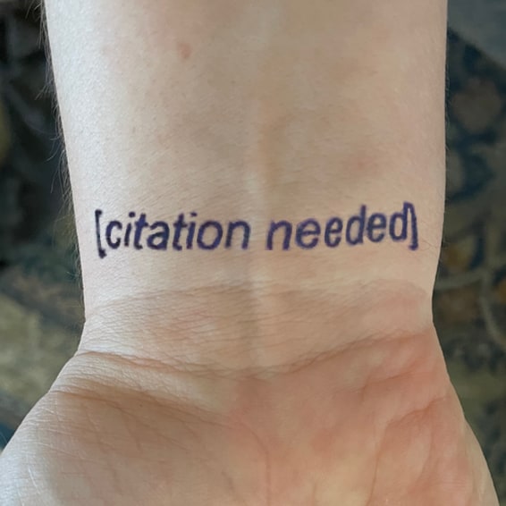 Photo of the inside of someone’s wrist, with the text “[citation needed]” — as often seen on Wikipedia — tattooed just below the heel of the hand.