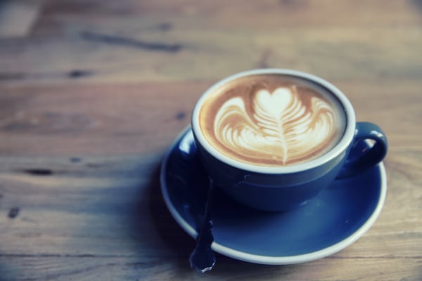 Photo of a pretty blue mug cup and saucer of latte.