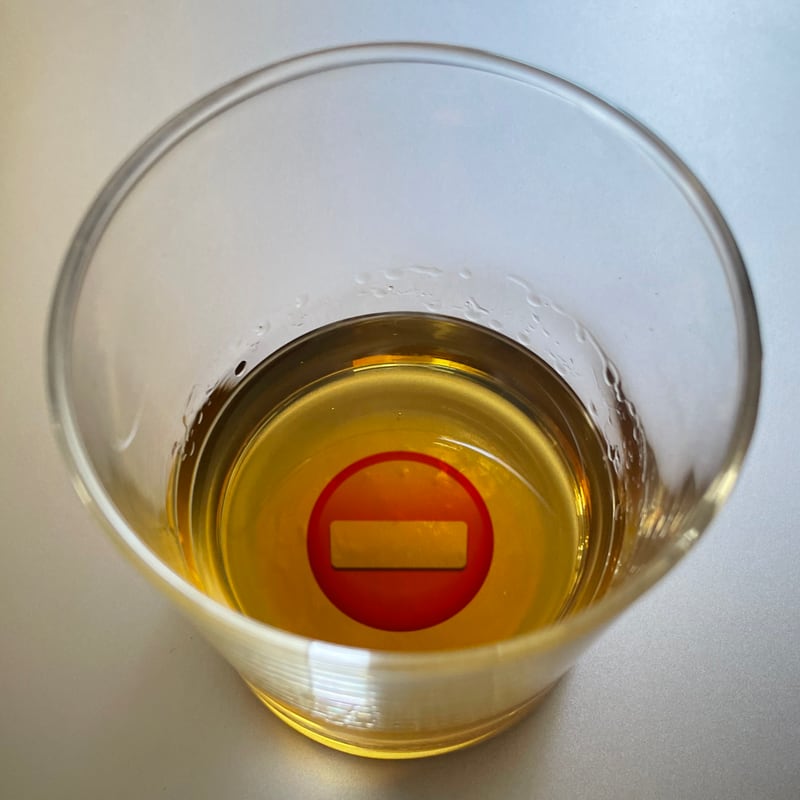 Photo looking down into a glass of whiskey with a “no entry” symbol at the bottom of the glass.