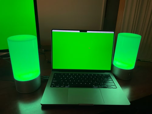Photo of a laptop with a bright green glowing screen, flanked by a pair of green lamps.