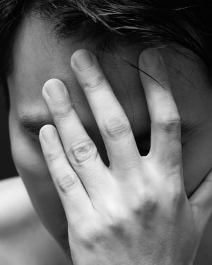 Photo of a man covering his face with his hand.