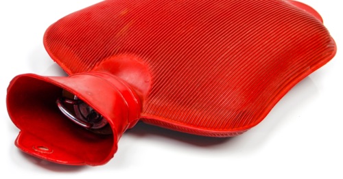 Artistic photograph of a red rubber hot water bottle, low angle, shallow depth of field, grainy.