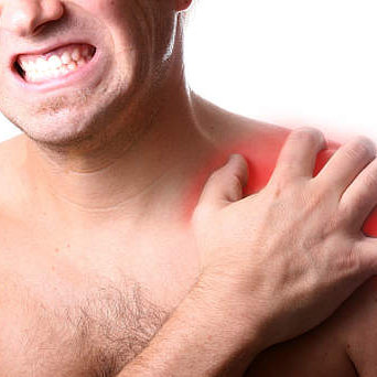 Photo of man grimacing, holding his shoulder.