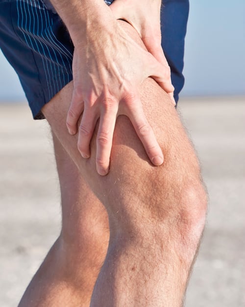 Photo of man in shorts holding knee, presumably because it hurts.