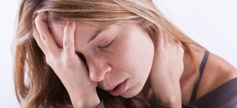 Photo of a woman with neck pain, holding her neck.