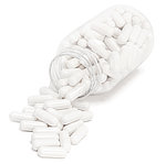 Photograph of a clear bottle of plain white pills spilling out onto a white surface.