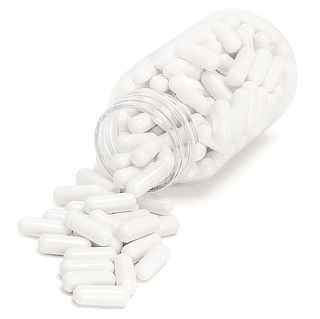 Photograph of a clear bottle of plain white pills spilling out onto a white surface.