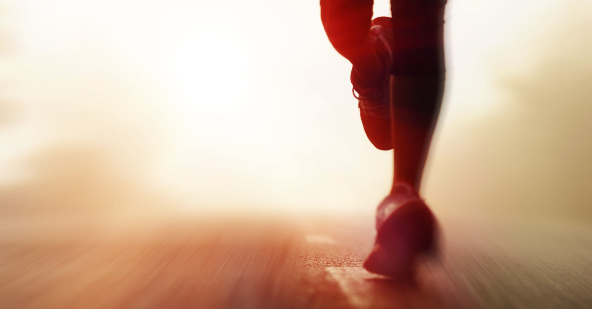 Photo of a runner’s legs on a road with a brightly lit but indistinct background.