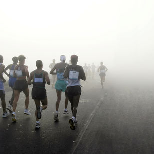 Photo of several marathoners in fog, running away from the camera.