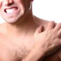 Photo of man grimacing holding her shoulder.