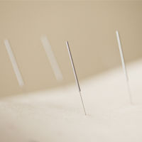 Close-up of an acupuncture needle inserted into out of focus flesh. Three other needles in the background.