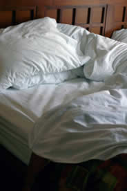 Photograph of an unmade bed, representing the relationship between sleep and back pain.