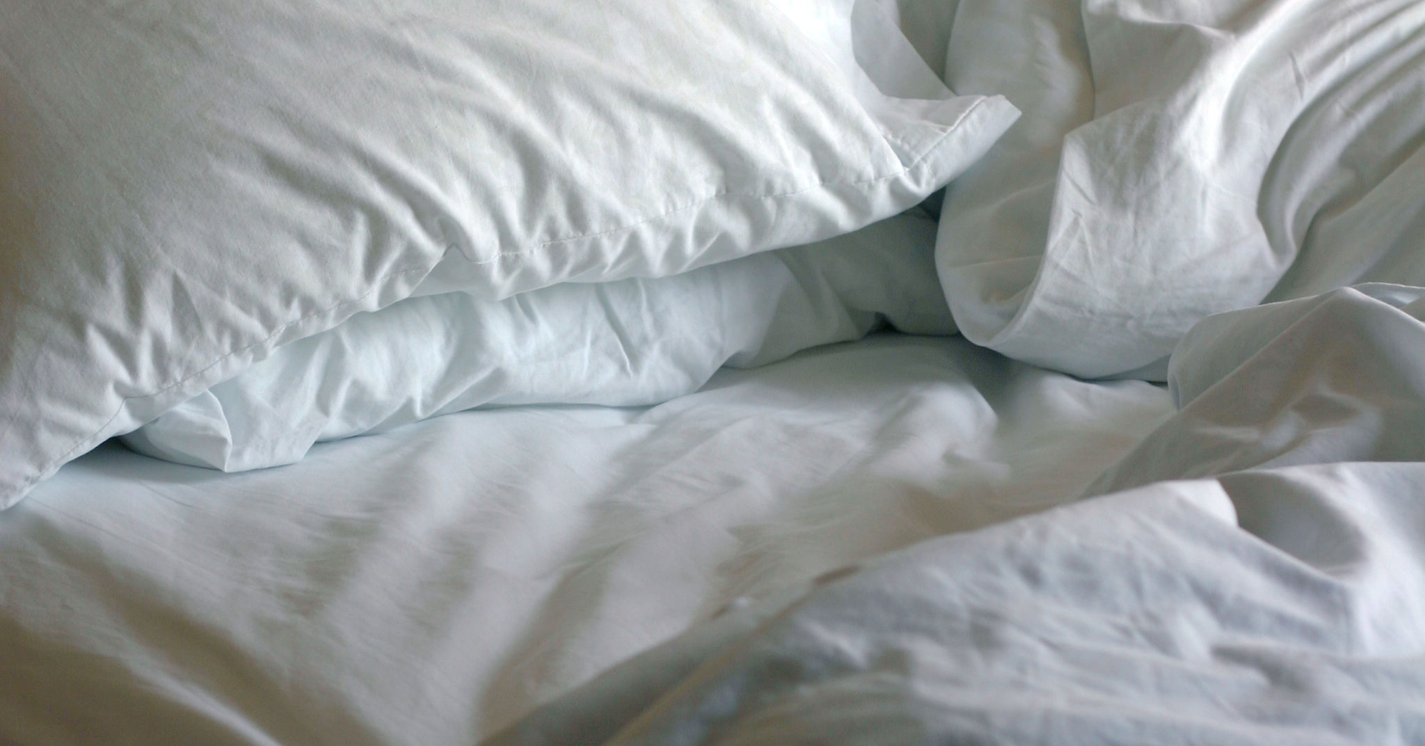 Photograph of an unmade bed, representing the relationship between sleep and back pain.