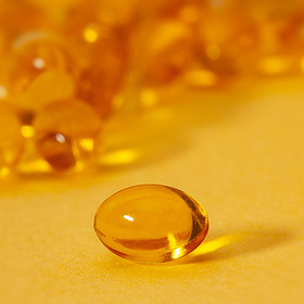 Photograph of shiny, brightly lit vitamin D gel capsules close up.