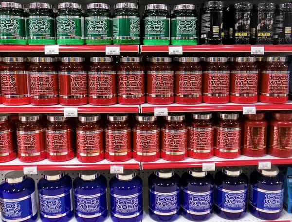 A photograph of large shelving unit stuffed with large buckets of whey powder.